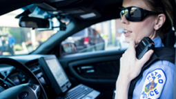 Police officer inside car keying up and speaking into shoulder-worn radio