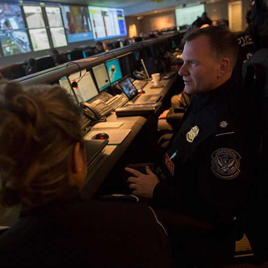 Man monitoring computer screens with colleague. 