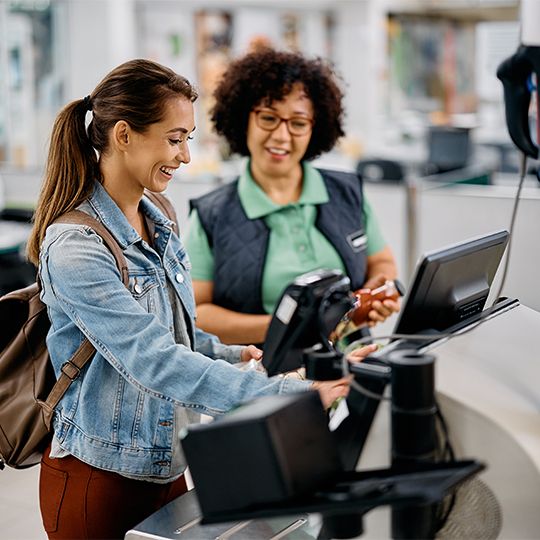 Retail staff helping woman at checkout